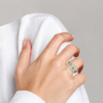 white and yellow gold emerald and diamond band on finger
