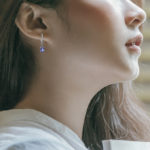 white gold tanzanite and diamond dangle earrings on model