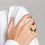 yellow gold emerald and diamond ring on finger