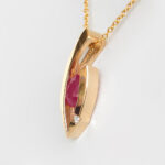 side view of yellow gold oval ruby and diamond pendant
