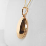 side view of yellow gold round locket